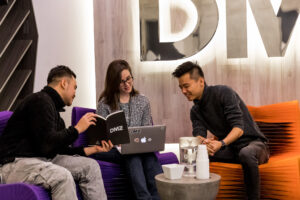 three startup founders sitting at the DMZ in a meeting looking at a laptop
